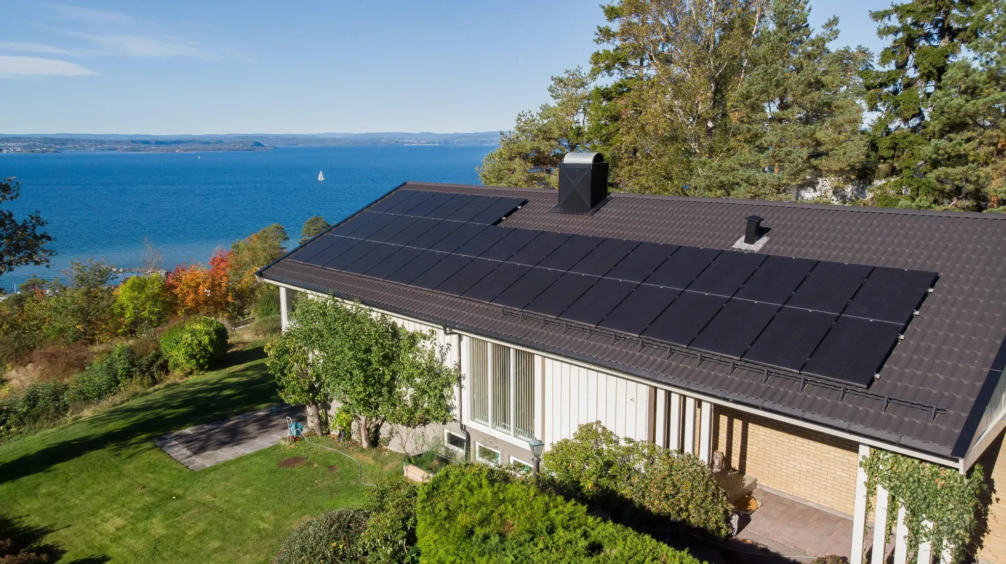 Et hvitt hus med sjøutsikt og solceller på taket
